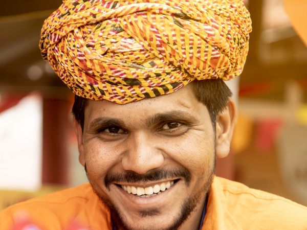 A smiling man wearing a traditional turban and a work identity card.