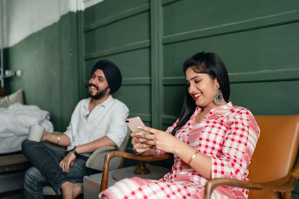 Two people sitting at home, looking together at a mobile phone.