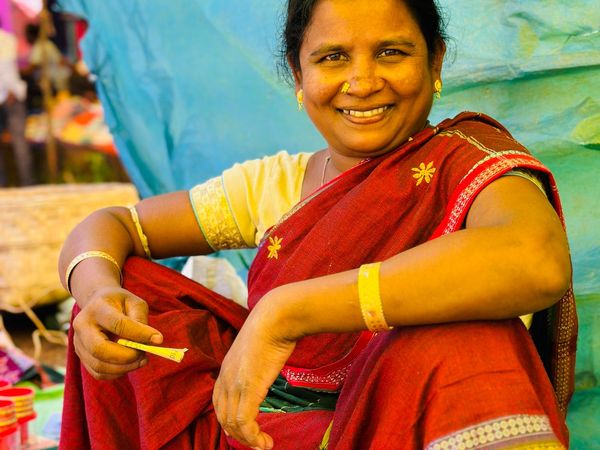 A woman in a bright saree smiling at her market stall.